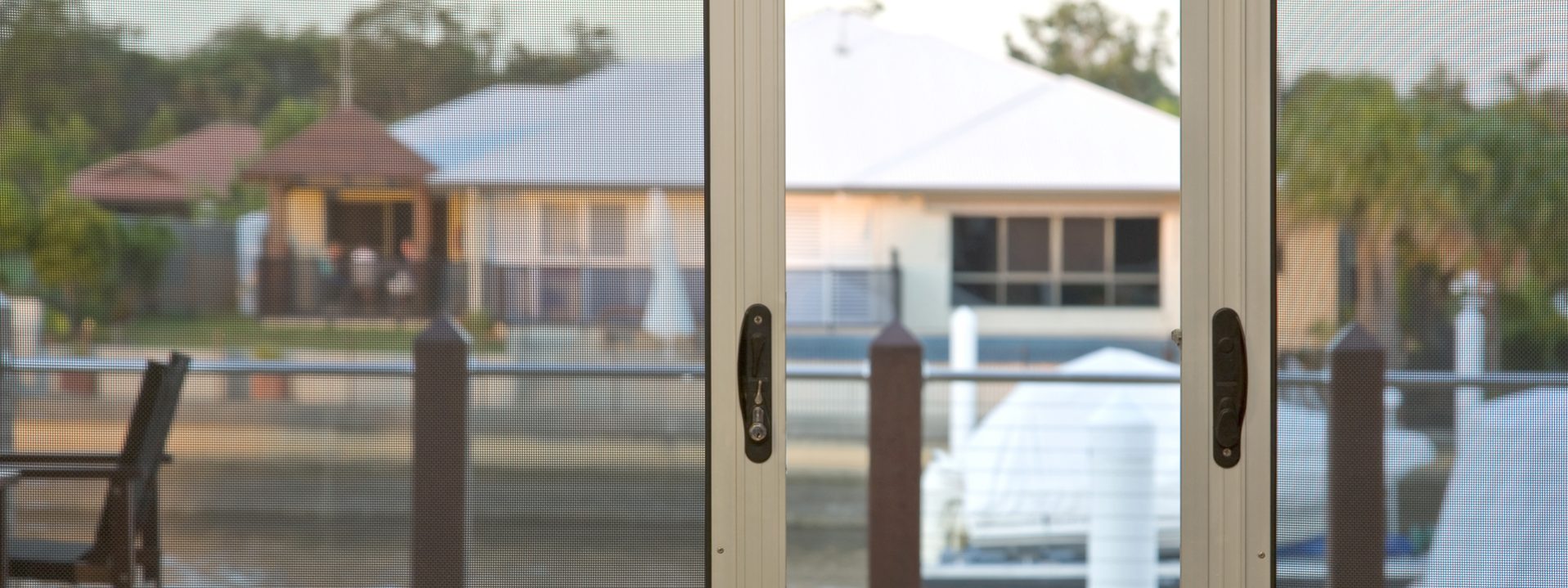 A close-up of an aluminium sliding security screen door located within a Hillary backyard.