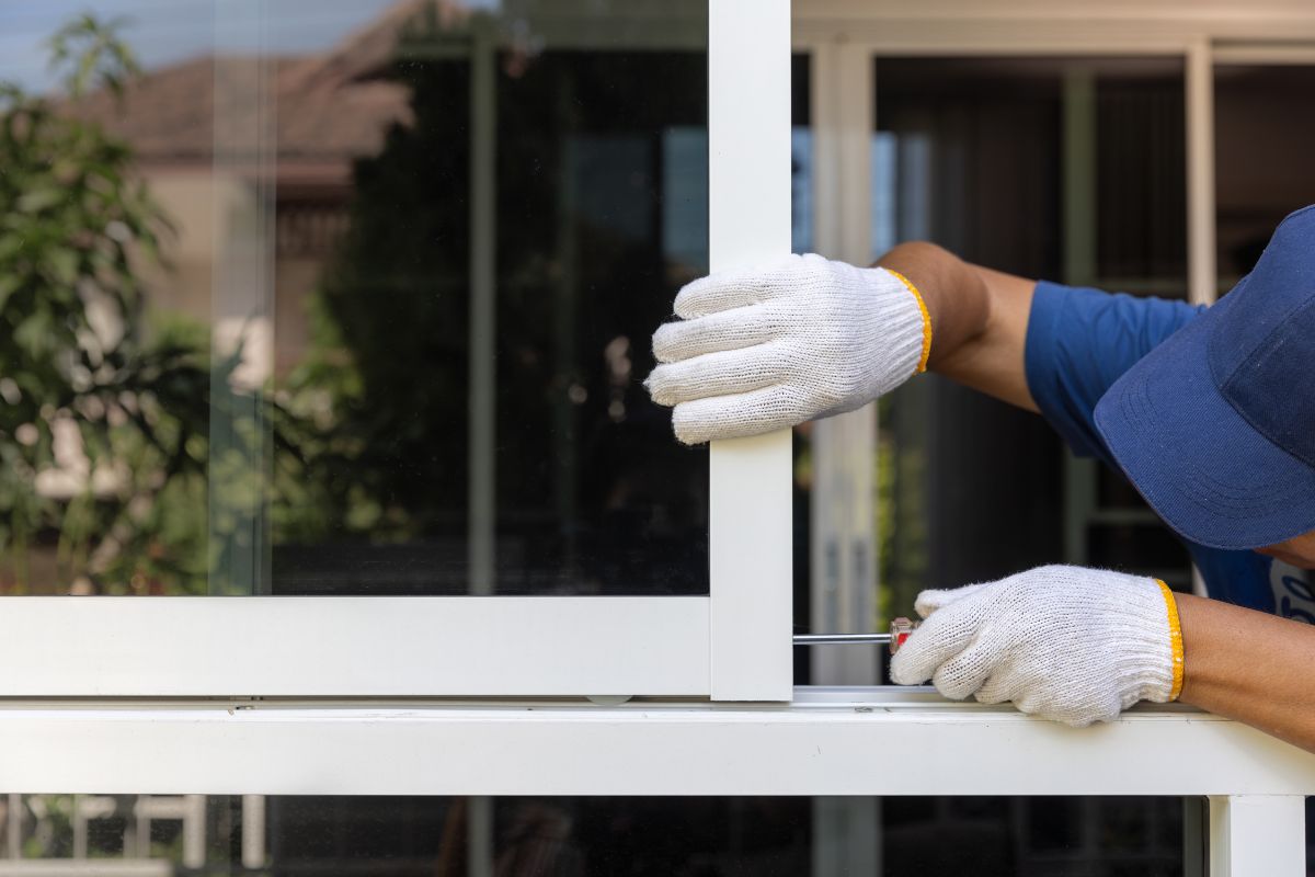 A repairman working on installing an aluminium window frame.